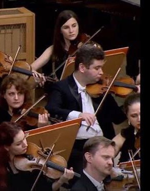 Tatev Muradyan playing in the violin section of a symphony orchestra