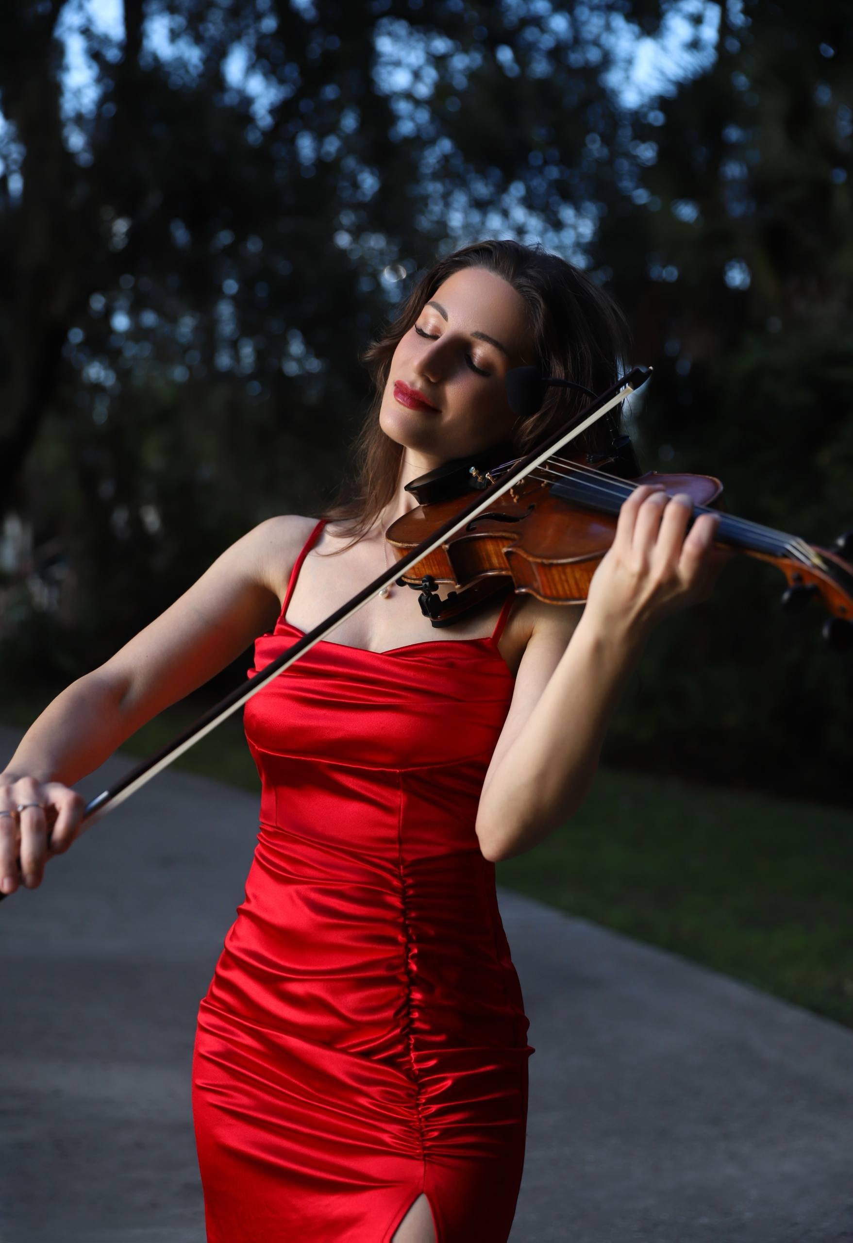 Tatev Muradyan in a red gown playing violin outdoors