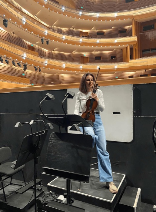 Tatev Muradyan with her violin on stage in a concert hall